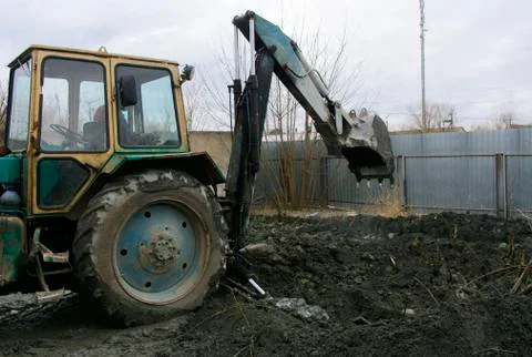 An old Soviet tractor digs and loads waste stone processing near the shop 库存照片