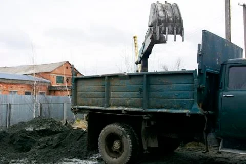 An old Soviet tractor digs and loads waste stone processing near the shop 스톡 사진
