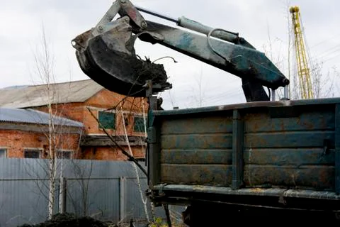 An old Soviet tractor digs and loads waste stone processing near the shop 库存照片