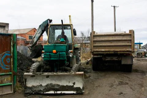 An old Soviet tractor digs and loads waste stone processing near the shop Stock Photos