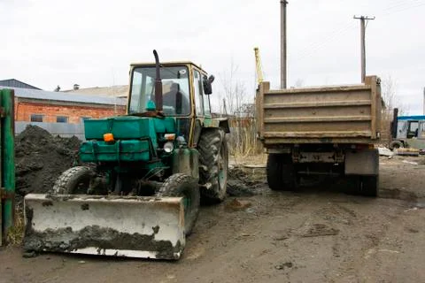 An old Soviet tractor digs and loads waste stone processing near the shop 库存照片