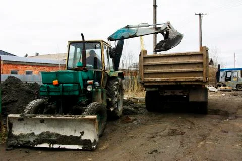 An old Soviet tractor digs and loads waste stone processing near the shop Foto stock