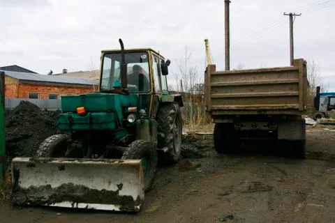An old Soviet tractor digs and loads waste stone processing near the shop Stock Photos
