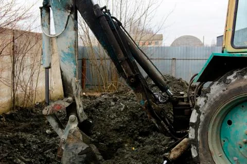 An old Soviet tractor digs and loads waste stone processing near the shop Stock Photos