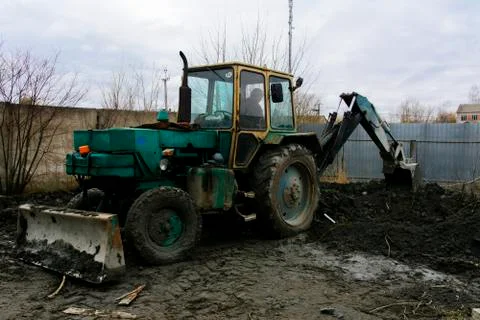 An old Soviet tractor digs and loads waste stone processing near the shop Stock Photos