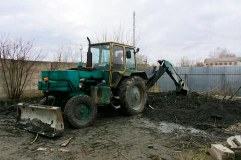 An old Soviet tractor digs and loads waste stone processing near the shop Stock Photos