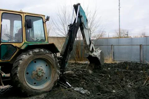 An old Soviet tractor digs and loads waste stone processing near the shop Stock Photos