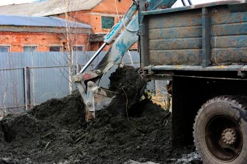 An old Soviet tractor digs and loads waste stone processing near the shop Stock Photos