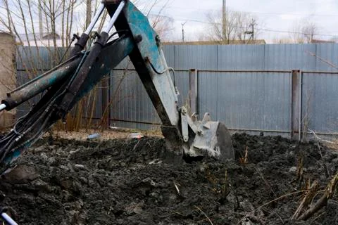 An old Soviet tractor digs and loads waste stone processing near the shop Stock Photos
