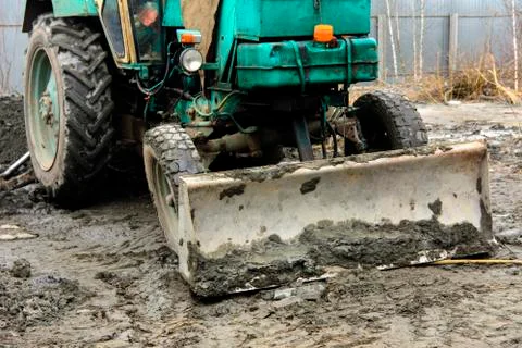 An old Soviet tractor digs and loads waste stone processing near the shop Stock Photos