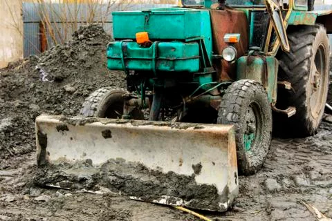 An old Soviet tractor digs and loads waste stone processing near the shop Stock Photos