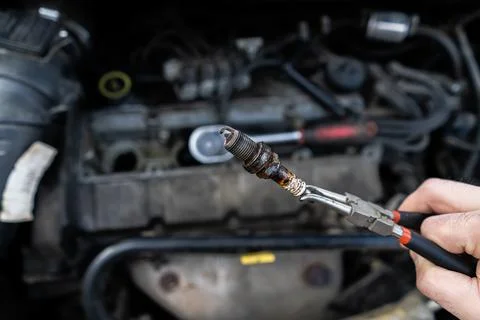 An old spark plug in the hands of a master against the background of the engi Stock Photos