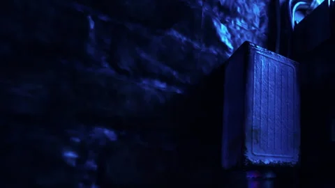 Old speaker stands against a wall in a dark room with blue lights Stock Footage 344059207