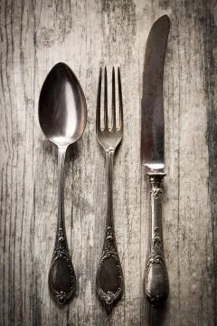 Old spoon, fork and knife on wooden background Stock Photos