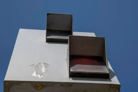 Old square flash unit against blue sky at a street with red flash Stock Photos