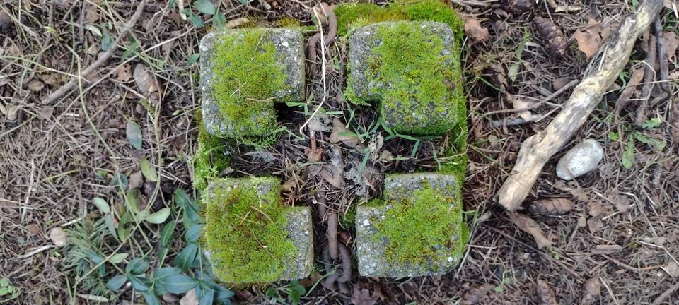 Old square mossy brick with rusty metal chain Stock-Fotos