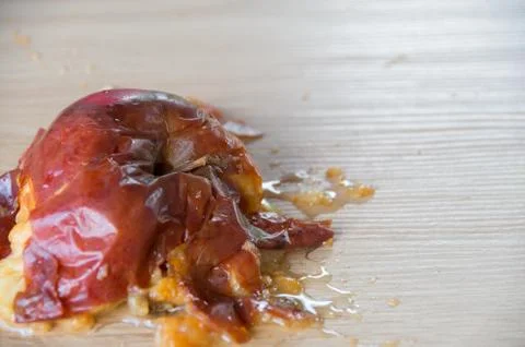 Old squuashed rotten apple isolated on a wooden bench top Stock Photos