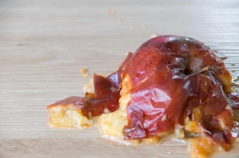 Old squuashed rotten apple isolated on a wooden bench top Stock Photos