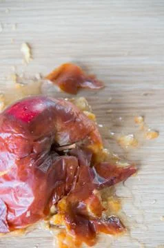 Old squuashed rotten apple isolated on a wooden bench top Stock Photos