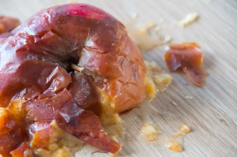 Old squuashed rotten apple isolated on a wooden bench top Stock Photos
