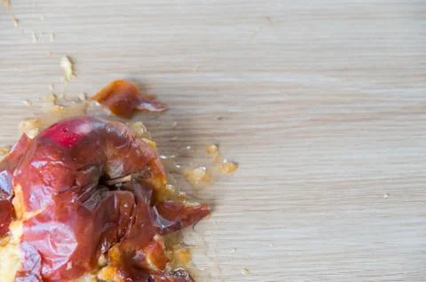 Old squuashed rotten apple isolated on a wooden bench top Stock Photos