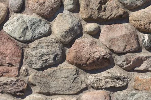 Old stable stone wall with rows of nature masonry stones. Brickwork with indi Stock Photos