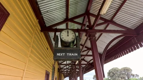 Old Station Clock Reading Next Train on Empty Rural Platform Stock Footage 337633472