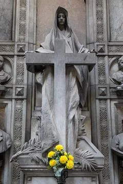 Old statue with cross in cemetery. Dramatic mysterious figure, no people. Stock Photos
