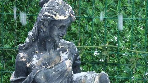Old statue under falling snow in front of green background Stock Footage 220258744