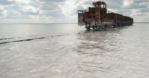 Old steam-powered train moves along sunken rail, water almost hides rails Stock Footage 118301098