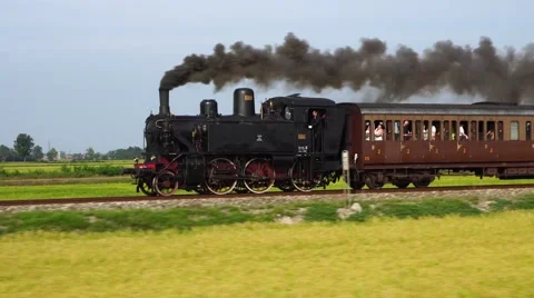 Old steam train and antique carriages run on the tracks between rice fields Stock Footage 67455953