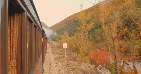 Old steam train on handheld shot side view while passing through beautiful Stock Footage 332970074