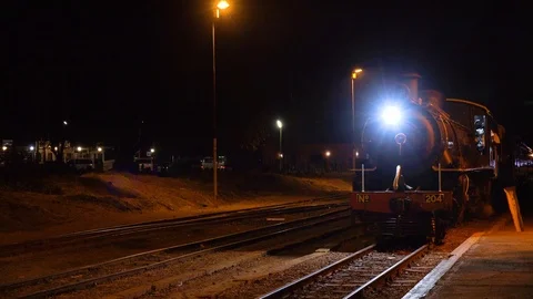 An old steam train pulls into a station at night in Zimbawbwe, Africa, with Vidéo 113200680