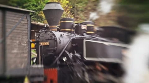 Old steam train slowly driving past a wooden cargo wagon on railway tracks,.. Stock Footage 339414354