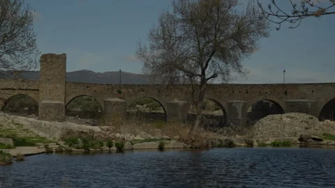 Old stone arch bridge spanning a calm river in Puente del Congosto Stock Footage 335461272
