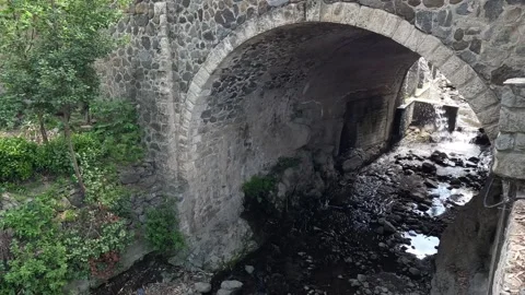 Old stone arched bridge over a mountain stream Stock Footage 240647068