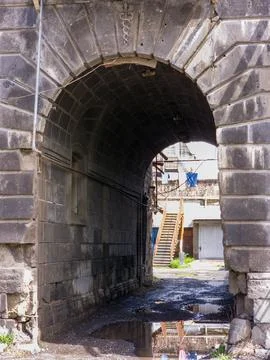 Old stone archway frames view of alley, ladder, and building Foto stock