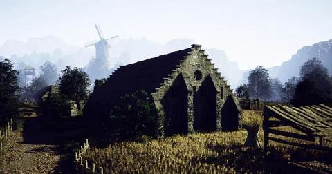 Old stone barn beside windmill in countryside landscape during daytime Ilustración de archivo