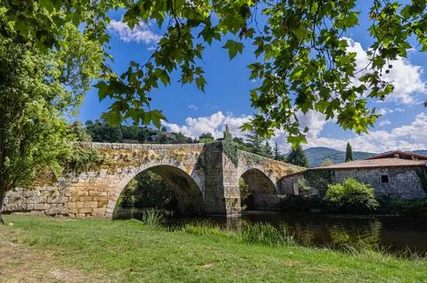 Old stone bridge arching over river in summer landscape Foto stock