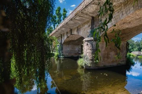 Old stone bridge arching over tranquil river Foto stock