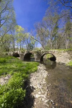 Old stone bridge crossing Doubrava river near Zasmuky in Czechia surrounded.. Stock Photos