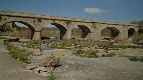 Old stone bridge with multiple arches crossing a low water river featuring .. Stock Footage 335462327