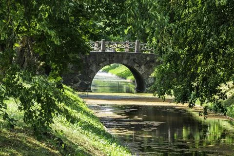 Old Stone Bridge Over the River and Lush Green Foliage Stock Photos