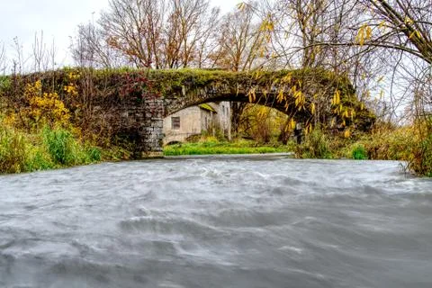 Old stone bridge over a small fast river. time is mercilessly in man s buildings Stock Photos