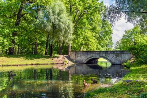 Old stone bridge in the park through a small river Stock Photos