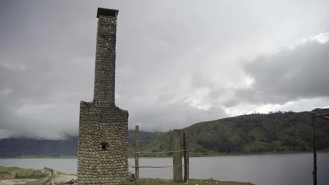 Old stone building with chimney in front of a lake surrounded by mountains  Stock Footage 277468750