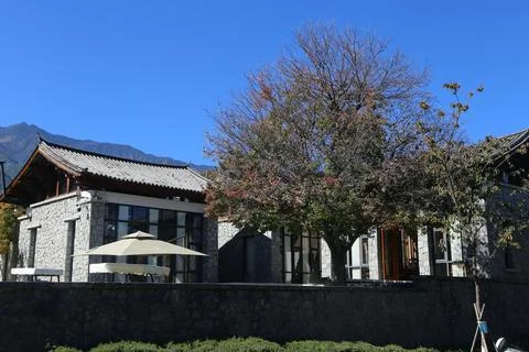 An old stone building frames a new, modern two-story hotel with white walls.. Stock Photos