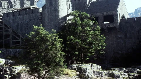 Old stone castle structure beside green trees and rocky terrain Stock Footage 344402477