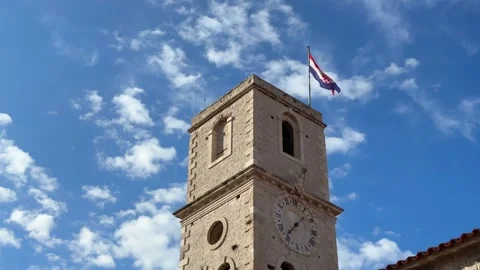 Old stone clock tower with the flag of Croatia waving in the wind against a Stock Footage 341663195