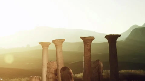 Old stone columns stand in a field during sunset near mountains Stock Footage 340214206
